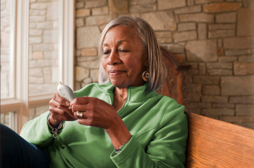 Older woman reading a device while seated in a cozy living space.