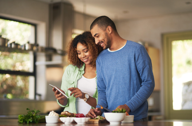 Couple reviewing a tablet while preparing healthy food in a kitchen