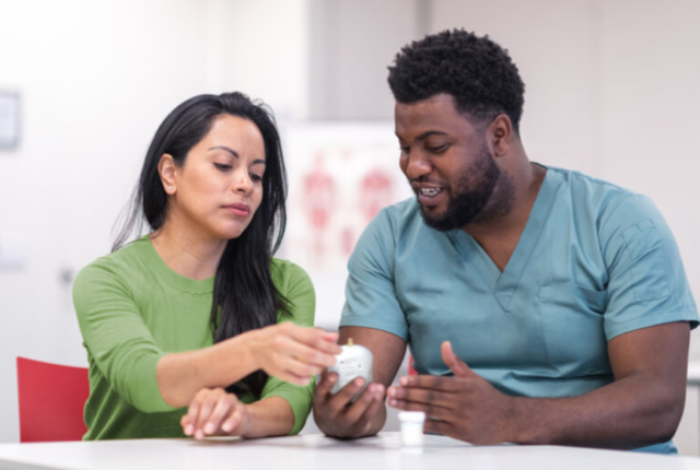 Healthcare professional discussing medication with a patient in a clinical environment.