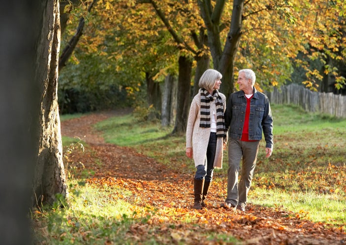 Couple outdoors holding hands on a path in a park.