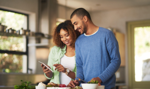 Couple reviewing a tablet while preparing healthy food in a kitchen